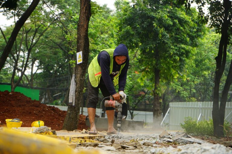 Trabalhador com colete de segurança usando martelete elétrico em obra